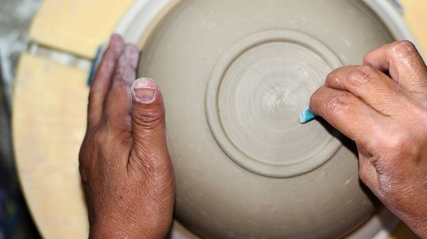 hands of a potter, creating an bowl on the circle, Pottery polishing process with 2 hands in the final step. Before entering the kiln. - Photo, Image