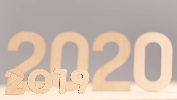 Big wooden 2020 numbers displacing 2019 on grey background - Fotoğraf, Görsel