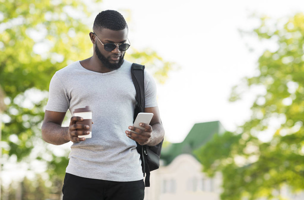 Pensivo homem africano usando celular e beber café para ir
 - Foto, Imagem