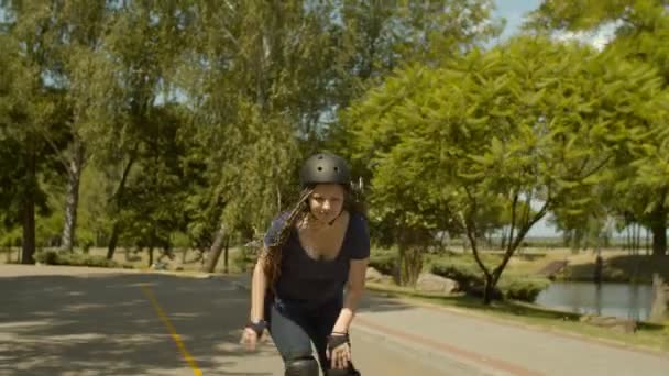 Active young female rollerblading at speed in park - Materiał filmowy, wideo