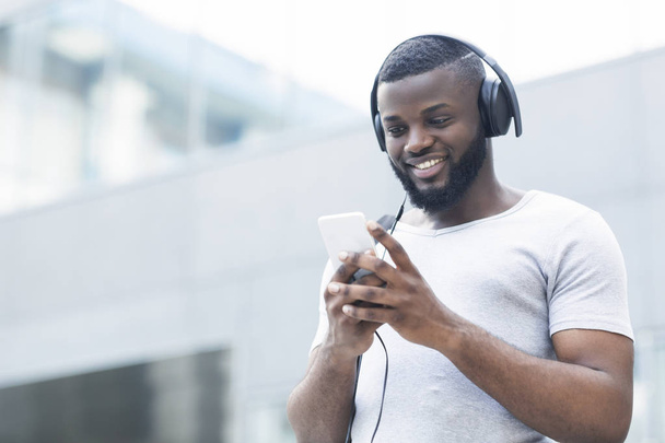 アフリカ人男性が携帯電話でテキストメッセージを送り、音楽を聴く - 写真・画像