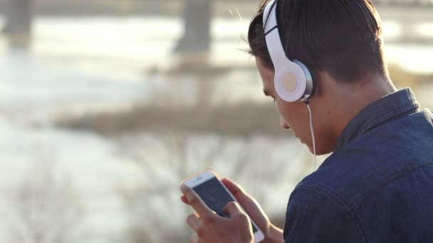 Close-up footage of a teenage boy listening to music with his headphones - Felvétel, videó