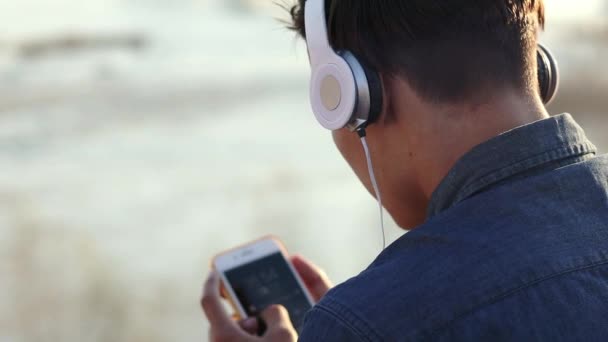 Close-up footage of a teenage boy listening to music with his headphones - Felvétel, videó