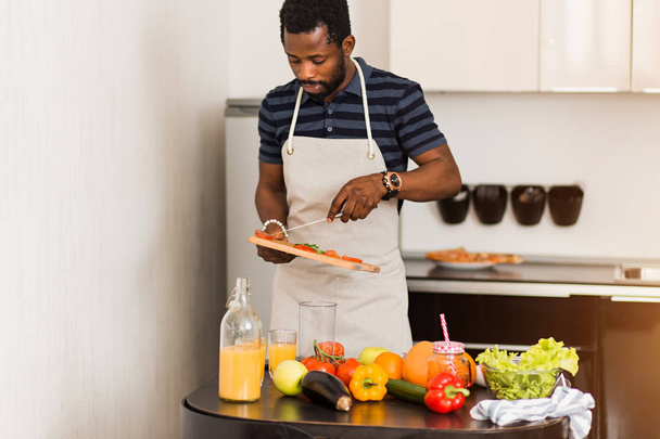 African man preparing healthy food at home in kitchen - Fotó, kép