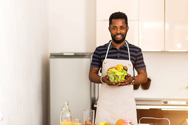 African man preparing healthy food at home in kitchen - Foto, Bild