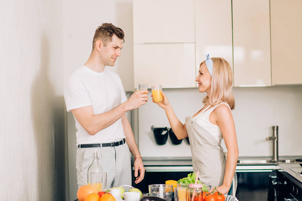 Couple making fresh organic juice in kitchen together - Φωτογραφία, εικόνα
