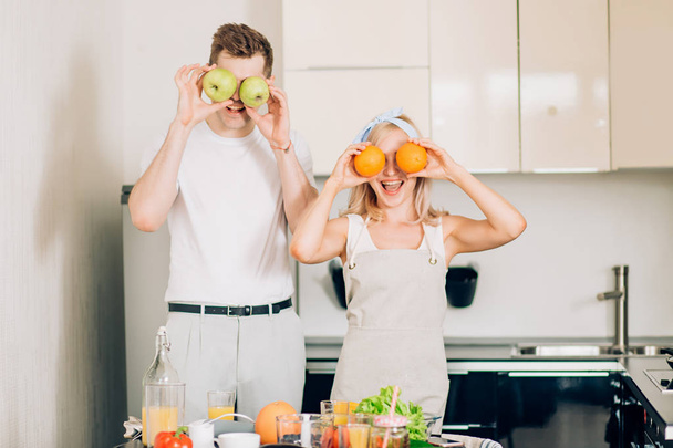 Couple making fresh organic juice in kitchen together - Foto, afbeelding