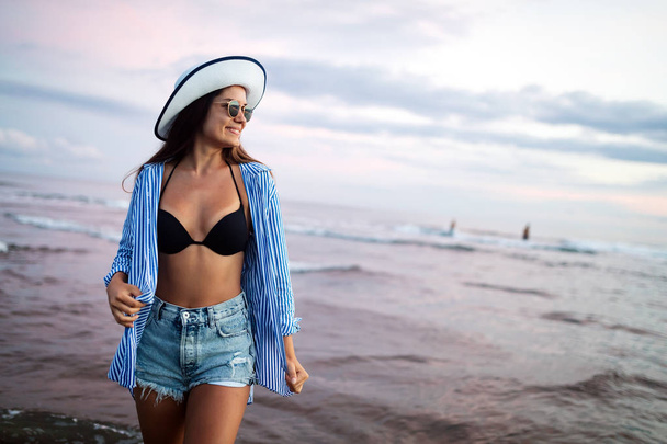 Beautiful girl on the beach at sunset. Summer vacation concept - Fotó, kép