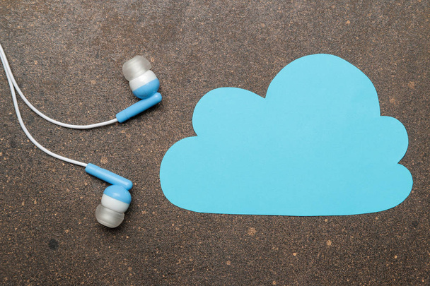 Kis kék fejhallgató a smartphone és a kék felhő sötét háttér. felülnézet. - Fotó, kép