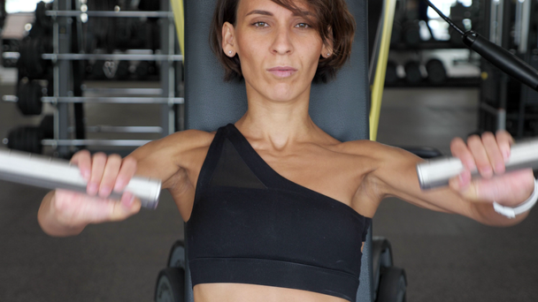 Mujer deportiva está haciendo ejercicios para los músculos de los brazos en la máquina de entrenamiento
. - Imágenes, Vídeo