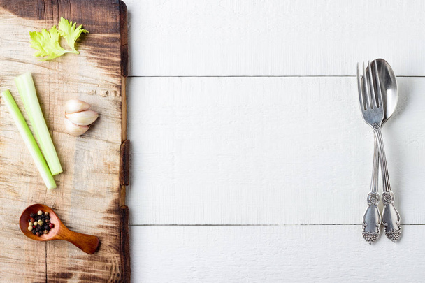 Cooking background concept. Cutting board, spice and cutlery on white wooden background. - Photo, Image