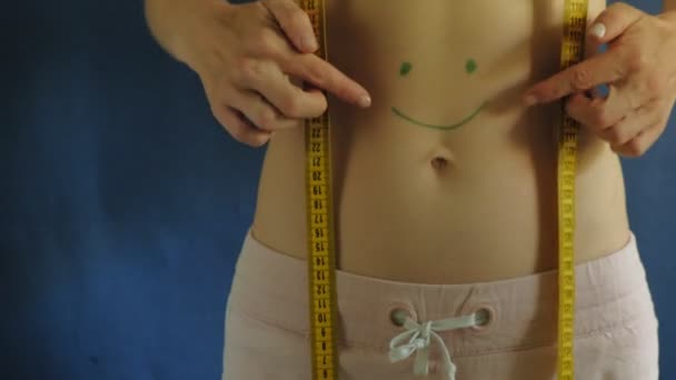 Kobieta z płaskim brzuchu. Zbliżenie na niebieskim tle. Zdrowa żywność, fitness - Materiał filmowy, wideo