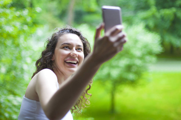 Young smiling girl is making selfie on a camera - Valokuva, kuva