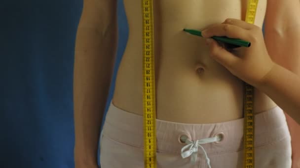 Kobieta z płaskim brzuchu. Zbliżenie na niebieskim tle. Zdrowa żywność, fitness - Materiał filmowy, wideo
