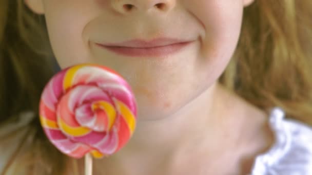 Little girl with a lollipop on a blue background. Close up portrait - Footage, Video
