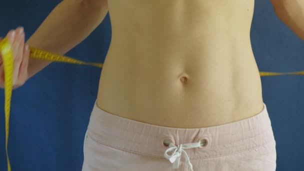 woman with a flat belly. Close-up on a blue background. Healthy food, fitness - Footage, Video