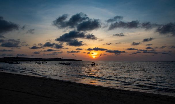 Sunset over calm ocean with balinese boat - Photo, Image