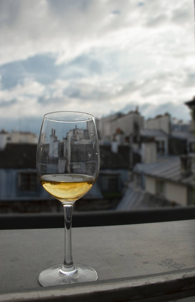 Glas Weißwein auf Fensterbank mit Blick auf die Dächer von Paris - Foto, Bild