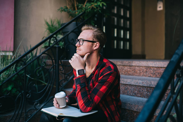 Thoughtful guy with hot beverage and notebook - 写真・画像