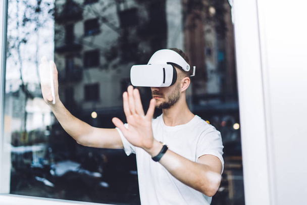 Millennial man in electronic digital glasses for testing cyberspace reality standing indoors using high technology for creating business design project, concept of interaction and visual watch - Foto, Imagen