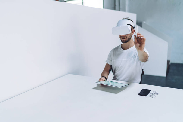 Cheerful male architect in virtual reality headset making 360 degrees panorama design construction project during work time in modern office, skilled man in goggles creating 3d dimension or immersion - Foto, Imagem
