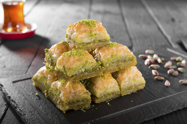 vue rapprochée de la boulangerie maison savoureuse avec des noix sur une table en bois. Dessert Ramadan turc Baklava aux pistaches et thé noir arabique - Photo, image