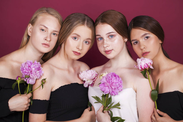 Four beautiful young girls on plum background in studio - Valokuva, kuva