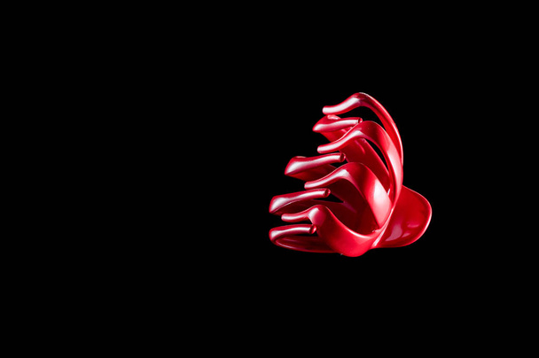 Red hairpin for the hair of the head on a black background, isol - Foto, afbeelding