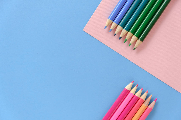 Creativo plano recostarse concepto de la escuela con lápices de colores sobre fondo azul y rosa. Concepto de arte mínimo. Vista superior, espacio de copia
. - Foto, imagen