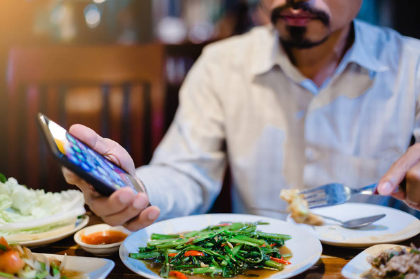 mies syö yhdessä pelaa älypuhelin. Elämäntapa nykypäivänä
 - Valokuva, kuva