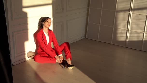 Atraktivní bruneta v červeném obleku sedí ve studiu - Záběry, video