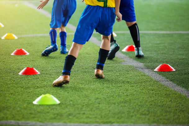dětský fotbalový hráč joggingu a skáčou mezi značkami kužele na bla - Fotografie, Obrázek
