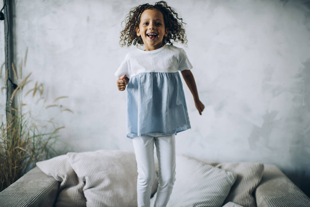 Laughing girl jumping on sofa - Foto, afbeelding