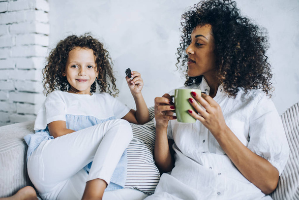 Adorable girl with mother having cookies and tea - Photo, Image