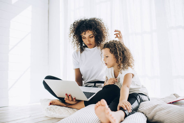 Relaxing woman with daughter using laptop in leisure - Фото, изображение