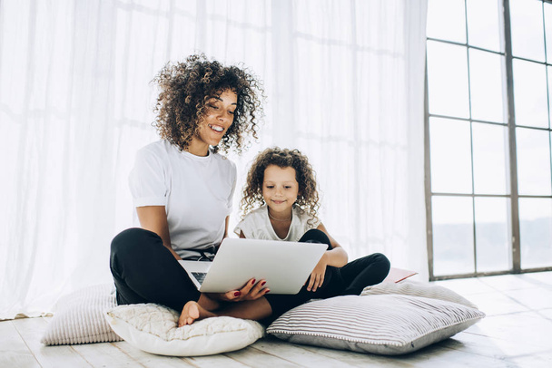 Lounging happy girl with mother using laptop - Photo, image