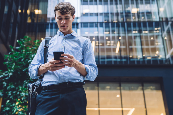 Formally dressed male executive manager in trendy clothes using mobile phone outdoors, Caucasian businessman sending text messages via smartphone connected to 4G internet for online chatting - 写真・画像