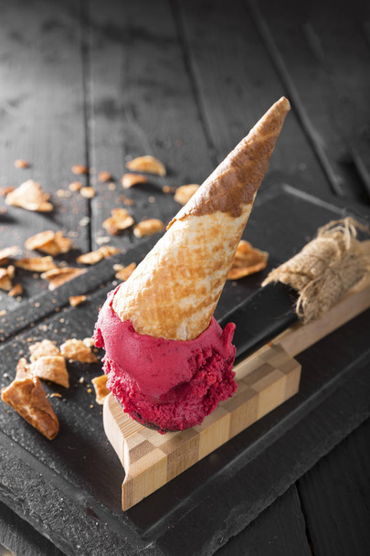 podrobný pohled na výtečný zmrzlinový krém s vaflovým kuželem v naběračce na dřevěném stole - Fotografie, Obrázek