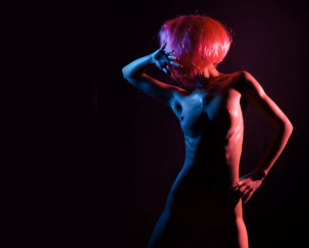 Mode kunst foto van sexy naakt stripper in de Night-Club. Perfect vrouwelijk lichaam met olie huid. Jong meisje met roze haar. Naakte borsten dansen. - Foto, afbeelding