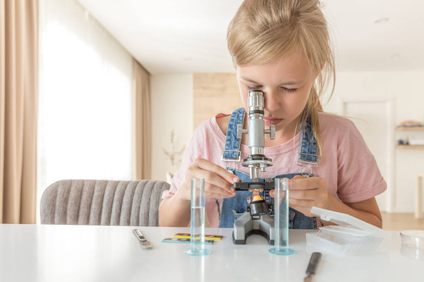 Девушка с микроскопом на домашнем обучении химии и игре
 - Фото, изображение