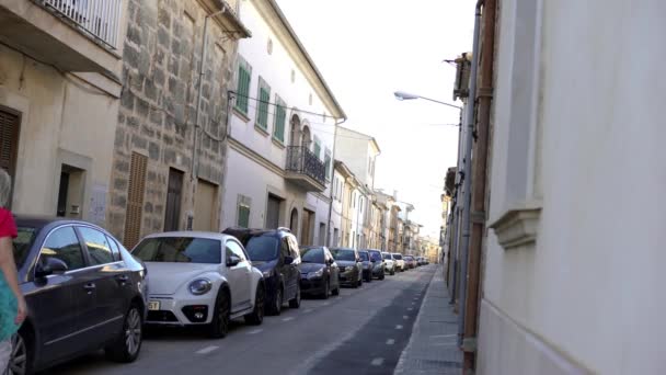 Θέα στα στενά δρομάκια της Ευρωπαϊκής πόλης το καλοκαίρι. Άρθρο. Γυναίκα περπατά με το σκυλί σε στενό δρόμο με σταθμευμένο σειρά των αυτοκινήτων στις καλοκαιρινές διακοπές - Πλάνα, βίντεο