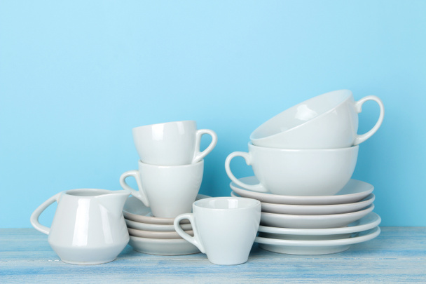 穏やかな青い背景に白いセラミック食器、ソーサー、カップの山。台所 用品. - 写真・画像