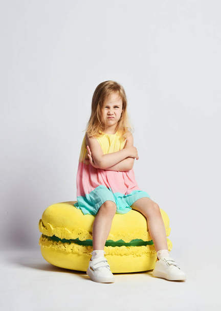 Cute little girl in bright clothes have fun at the birthday party fun room decoration candy macarons - Foto, imagen