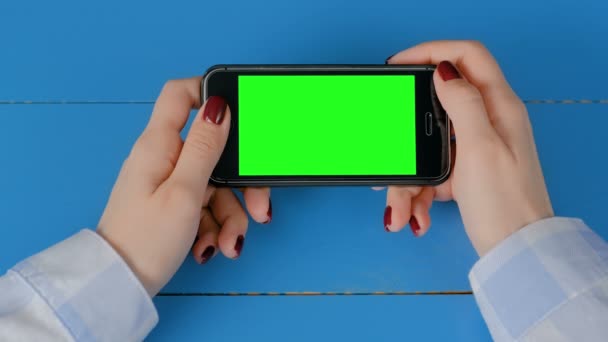Nő nézi a fekete okostelefon üres zöld képernyő - chroma kulcs koncepció - Felvétel, videó