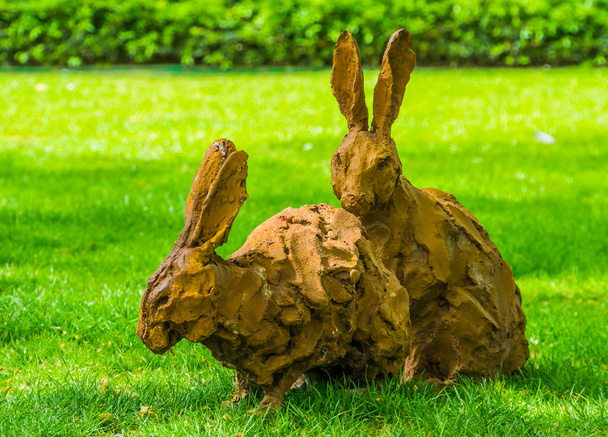 草の芝生の2つの茶色のイースターバニーの彫像、休日や庭のための装飾 - 写真・画像