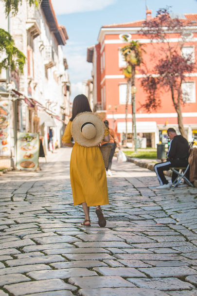 mujer en vestido amarillo con sombrero de paja poco caminar por la vieja ciudad turística de croacia
 - Foto, Imagen