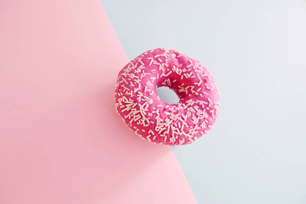 Juicy Pink Sprinkled Donut isolated on a Pink and Blue Background - Fotografie, Obrázek