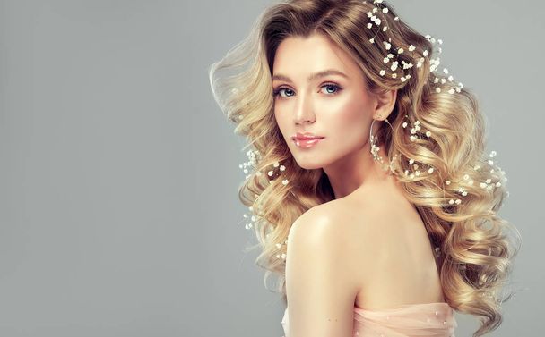Young, blonde haired woman with   wavy hair and flowers .Beautiful model with long,  hairstyle . - Photo, Image