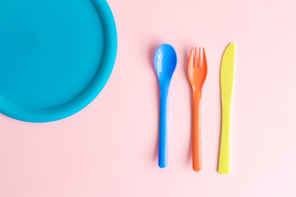 Plastic cutlery with plate against pastel pink background minimal creative food concept. - Foto, Bild