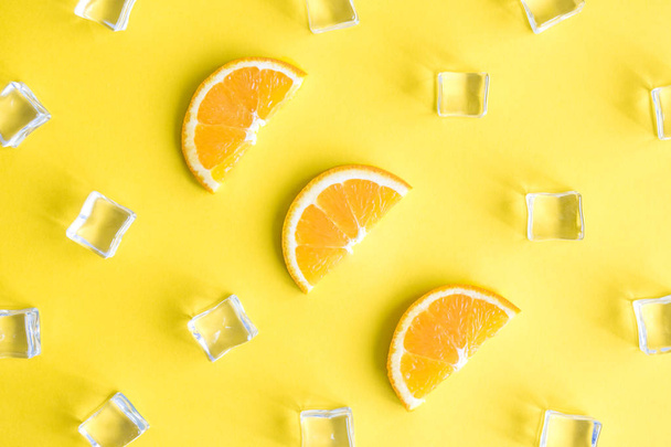 Top view tropical background composition made of orange fruit slices and ice cubes abstract on yellow. - Foto, imagen